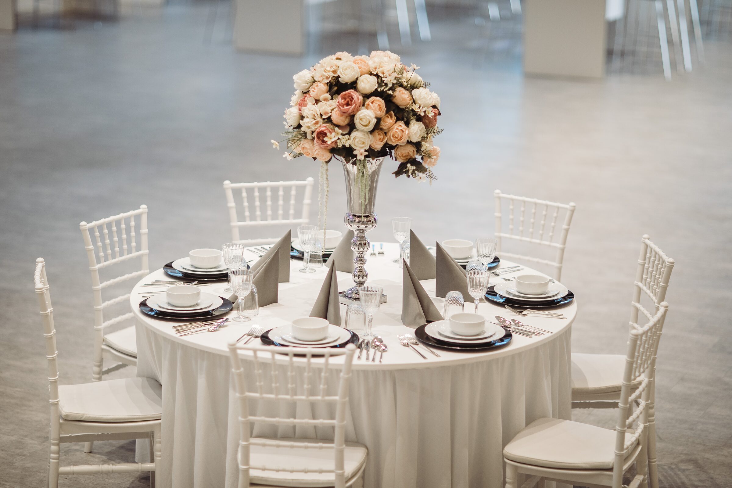 Runde Hochzeitstafel mit hohem Rosen-Arrangement im Saal der Visaal Event Location Krefeld
