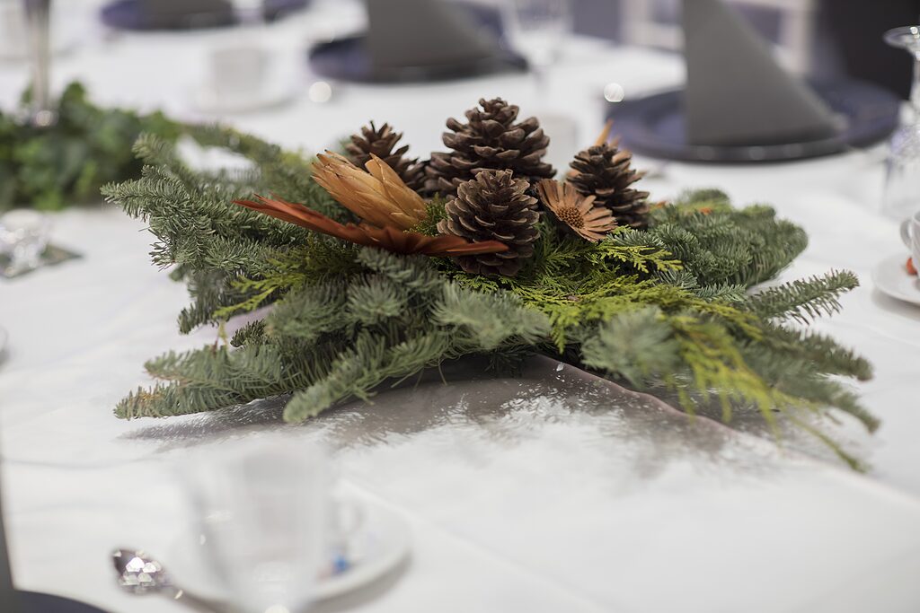 Adventsgesteck mit Tannenzweigen und Zapfen als Tischdekoration in der Weihnachtsfeier-Location Krefeld